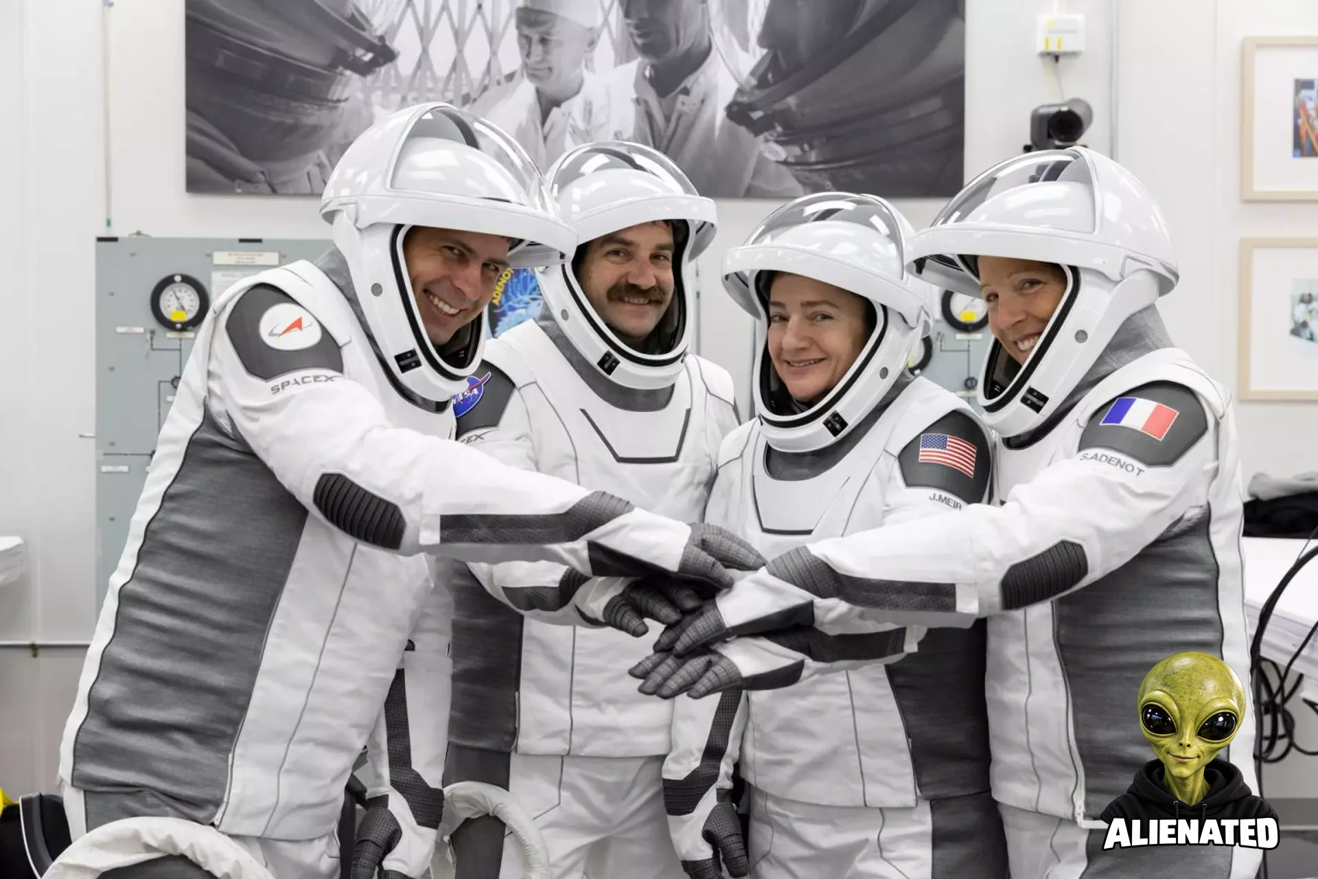 NASA’s SpaceX Crew-12 astronauts stand side by side in their spacesuits with face shields raised. They extend their arms forward, stacking their hands together in a team huddle while smiling. Pictured at the Neil A. Armstrong Operations and Checkout Building at Kennedy Space Center ahead of their Feb. 13, 2026 launch to the International Space Station, from left to right: Roscosmos cosmonaut Andrey Fedyaev, NASA astronauts Jack Hathaway and Jessica Meir, and ESA astronaut Sophie Adenot.