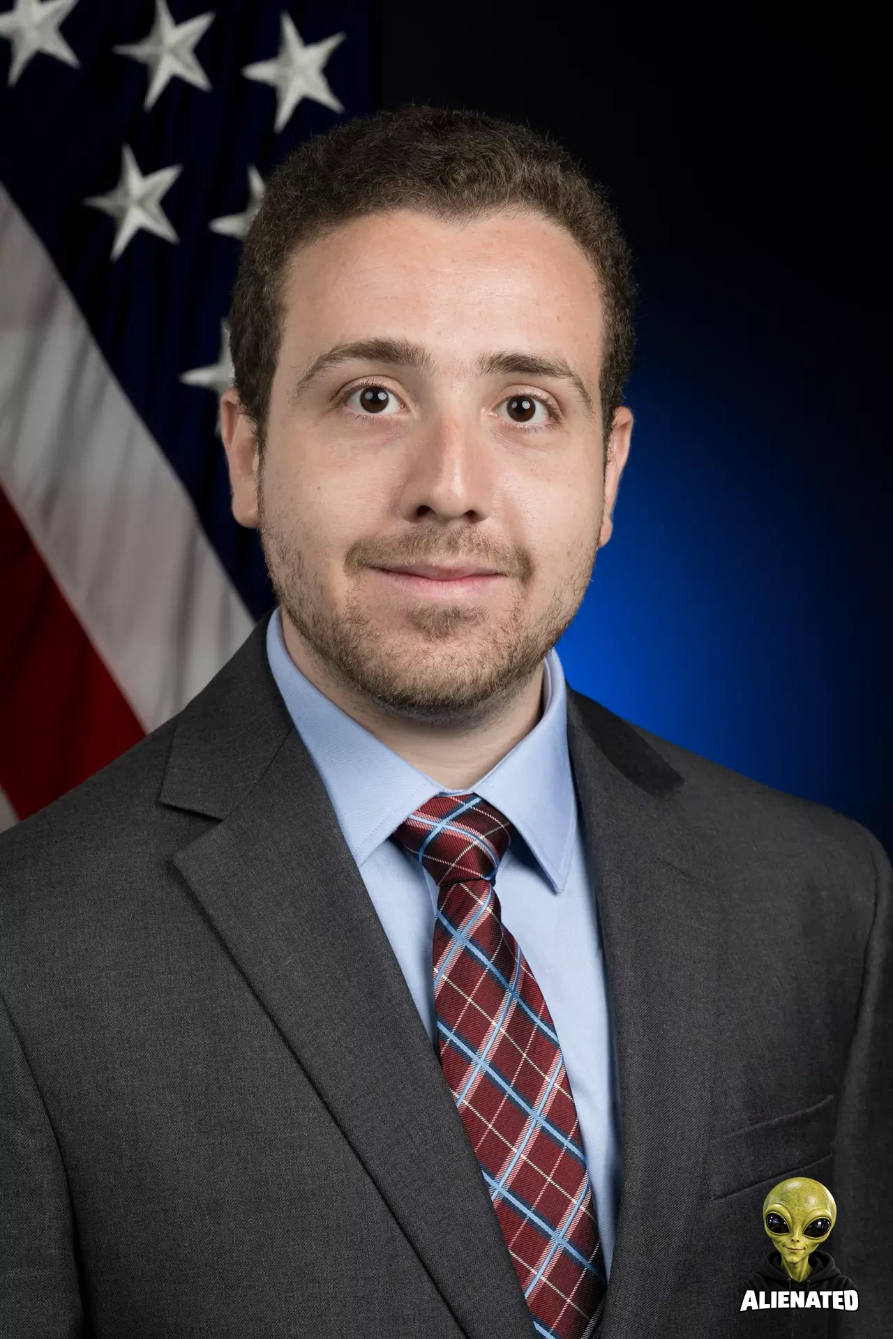 Official NASA portrait of Richard Spolzino, aerospace engineer, in front of an American flag backdrop