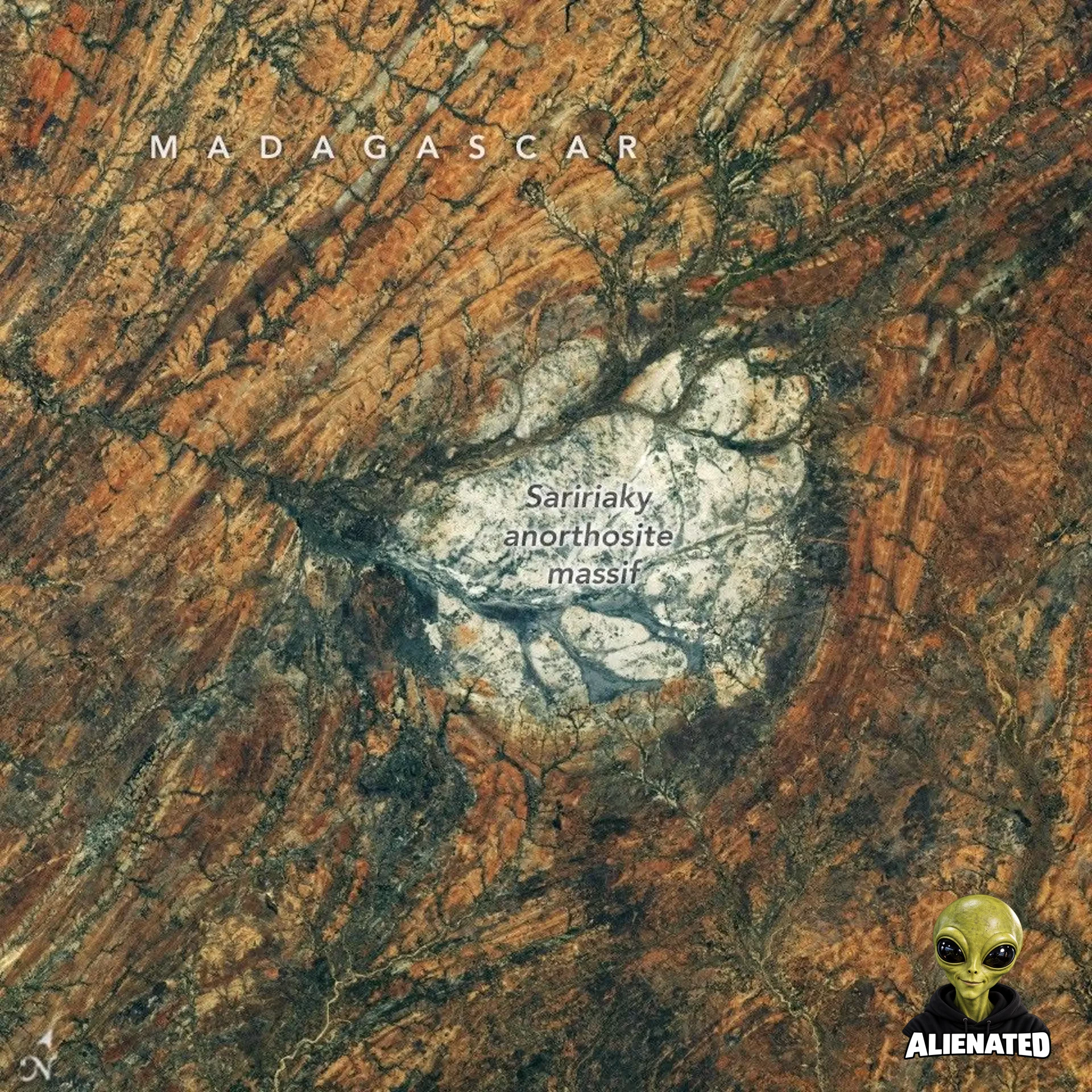 A round, white rock outcrop is surrounded by orange rocks with a north-south linear pattern. Branching riverbeds cut through the rock structures.